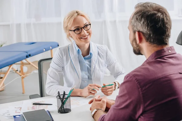 Lächelnder Physiotherapeut Weißen Kittel Schaut Patientin Bei Termin Klinik — Stockfoto