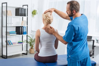 physiotherapist doing massage to woman on massage table in hospital clipart