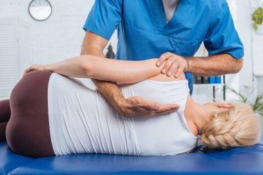 cropped shot of chiropractor massaging back of patient that lying on massage table in hospital clipart