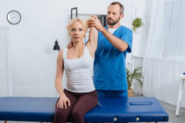portrait of chiropractor stretching womans arm on massage table in clinic