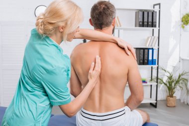 back view of man having chiropractic adjustment in clinic clipart
