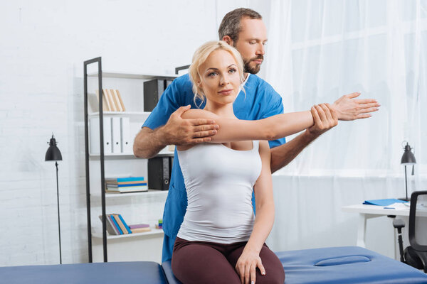 physiotherapist stretching patients arm on massage table in hospital