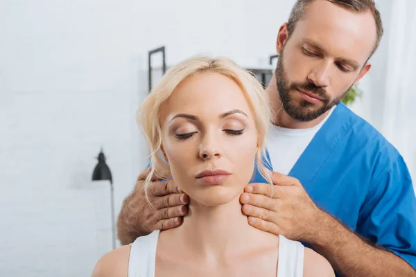 クリニックで若い女性の首をマッサージするマッサージの療法士の肖像画 — ストック写真
