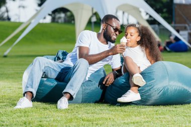 Afrikalı-Amerikalı babası kızı beanbag sandalye Park Tarih dondurma veren gülümseyen