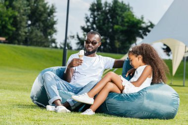 dondurma ve Park beanbag sandalye üzerinde oturan kızı ile Afrikalı-Amerikalı babası
