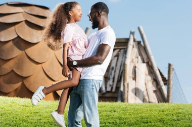 Eğlence Parkı yeşil tepe üzerinde Afro-Amerikan baba holding kız yan görünüm