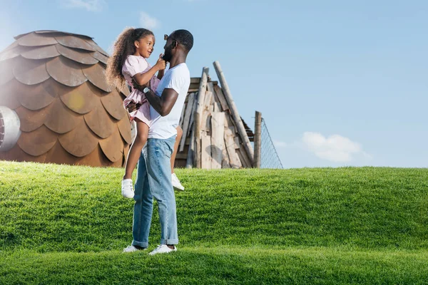 Afro Americano Pai Segurando Sorridente Filha Verde Colina Parque Diversões — Fotografia de Stock