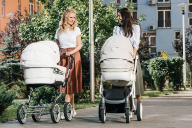 mothers walking with baby strollers on street clipart