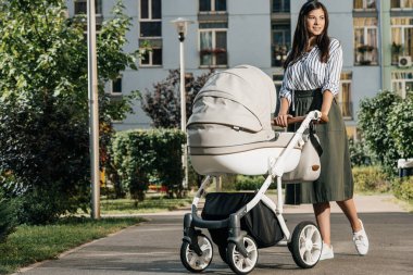 çekici anne bebek arabası ile sokakta yürürken ve uzağa arıyorsunuz