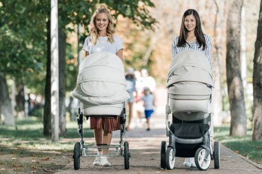 bebek arabasından park ve kameraya arıyor ile yürüme anneler gülümseyen