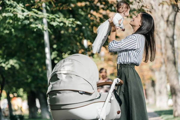 Glückliche Mutter Hält Baby Neben Kinderwagen Park — Stockfoto