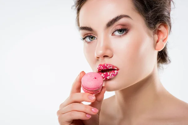 Όμορφη Νεαρή Γυναίκα Ψεκάζει Ζάχαρη Στα Χείλη Κρατώντας Ροζ Macaron — Φωτογραφία Αρχείου
