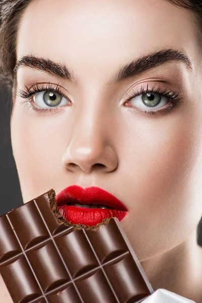 迷人的女孩与红嘴唇吃巧克力酒吧 孤立的灰色 — 图库照片