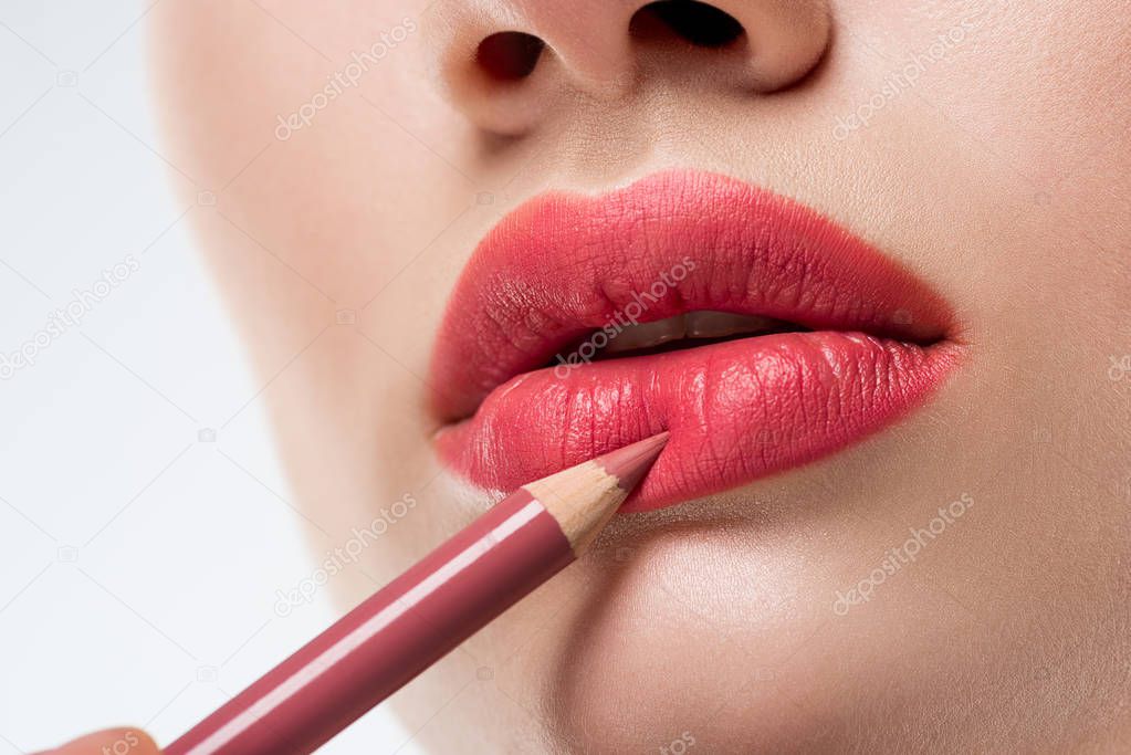 cropped view of woman applying lip pencil,  isolated on white 