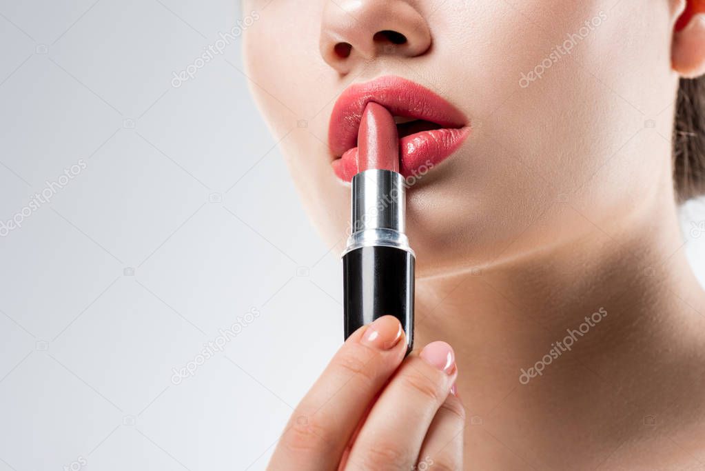 partial view of girl applying pink lipstick,  isolated on white