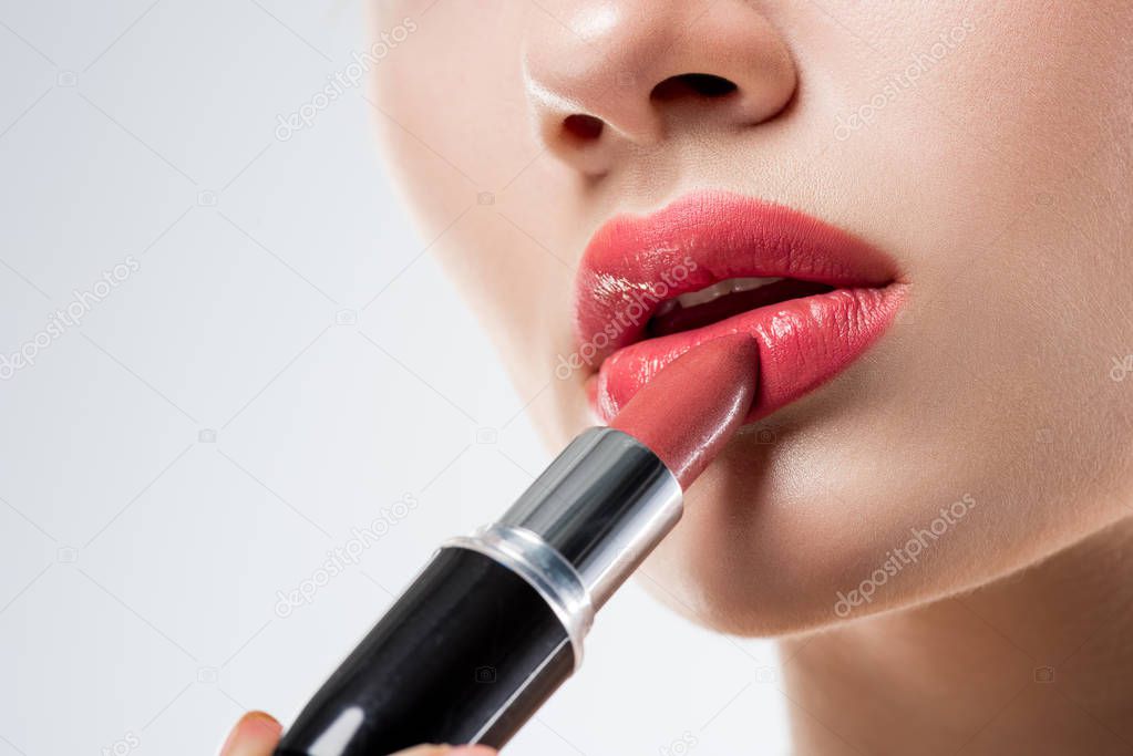 cropped view of woman applying pink lipstick,  isolated on white