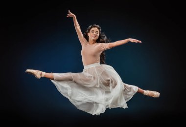 young ballerina in elegant clothing jumping on dark backdrop clipart