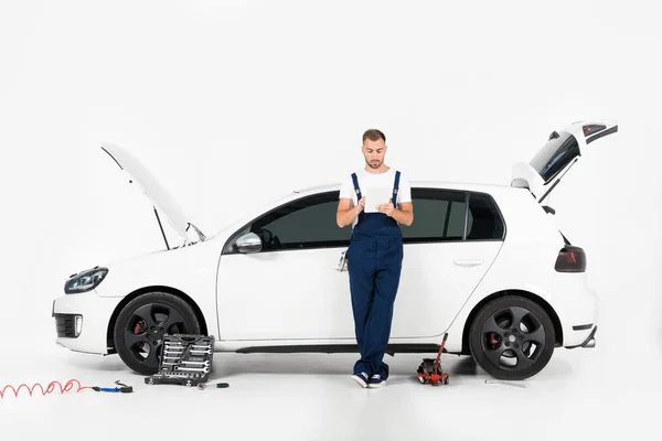 Przystojny Auto Mechanik Pochylony Samochód Pomocą Tabletu Białym — Zdjęcie stockowe