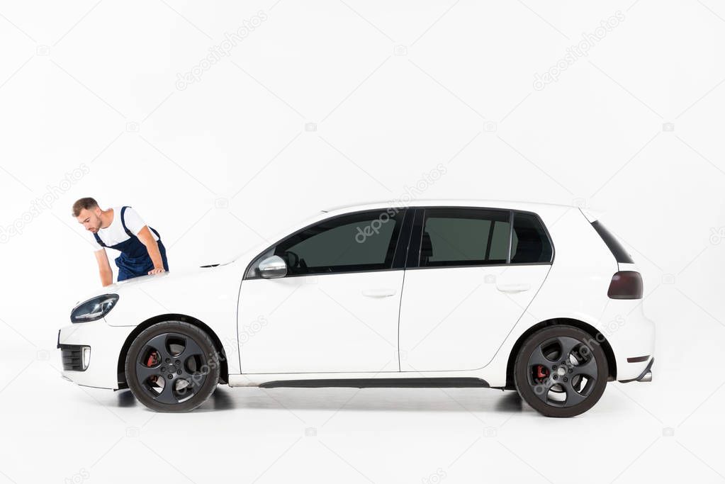 handsome auto mechanic cleaning car after repairing on white