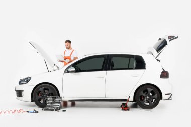 yakışıklı otomatik mekanik dizüstü car yakınındaki beyaz üzerinde açık kukuleta ile kullanma