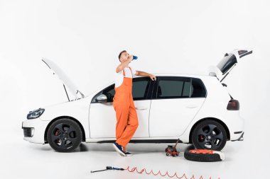 içme suyu ve araba beyaz üzerine eğilerek yakışıklı otomatik mekanik