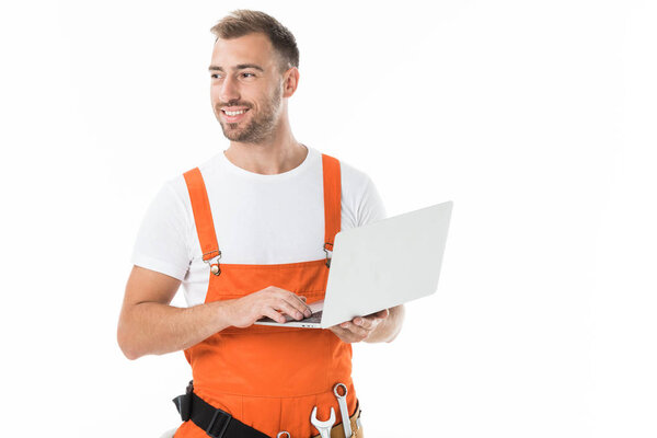 portrait of handsome auto mechanic in orange uniform holding laptop isolated on white