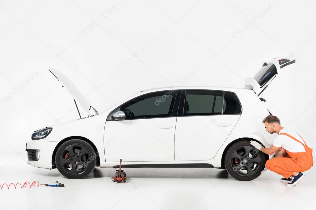 auto mechanic changing car tire on white