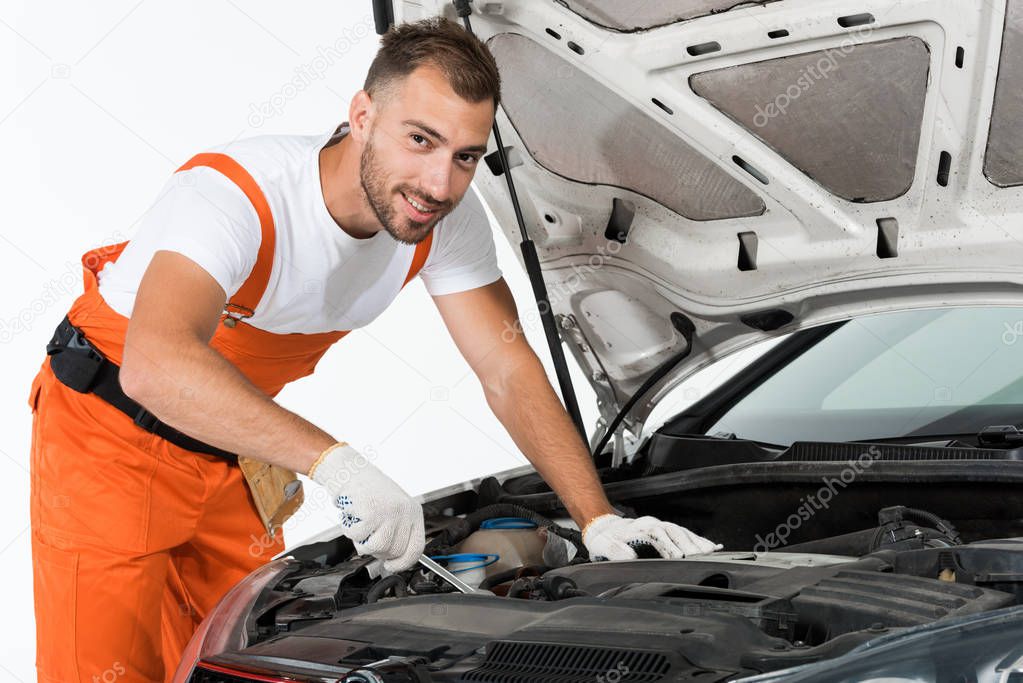 handsome auto mechanic auto mechanic repairing car with wrench on white
