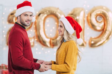 kaç evde 2019 yeni yıl ile altın balonlar elele santa şapkalar içinde gülümseyen