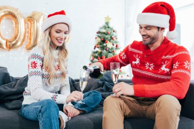 mutlu adam şampanya Noel ağacı ile evde gözlük içine dökme