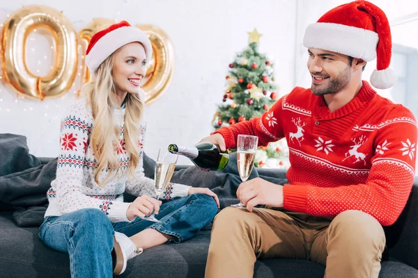 Sonriente Hombre Vertiendo Champán Copas Pareja Celebrando Navidad Casa — Foto de stock gratis