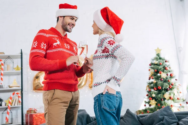 Jong Koppel Santa Hoeden Roosteren Met Champagneglazen Thuis Met Kerstboom — Gratis stockfoto