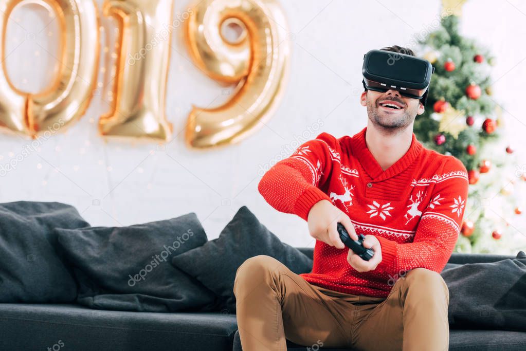 smiling man with vr headset and joystick playing video game during 2019 new year