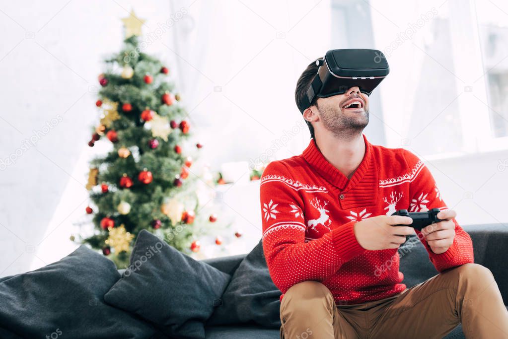 excited man playing game with virtual reality headset and joy pad on christmas eve