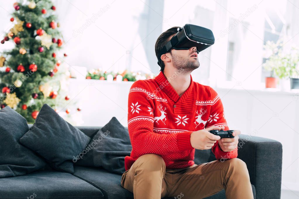 man with virtual reality headset and joystick playing video game on christmas eve