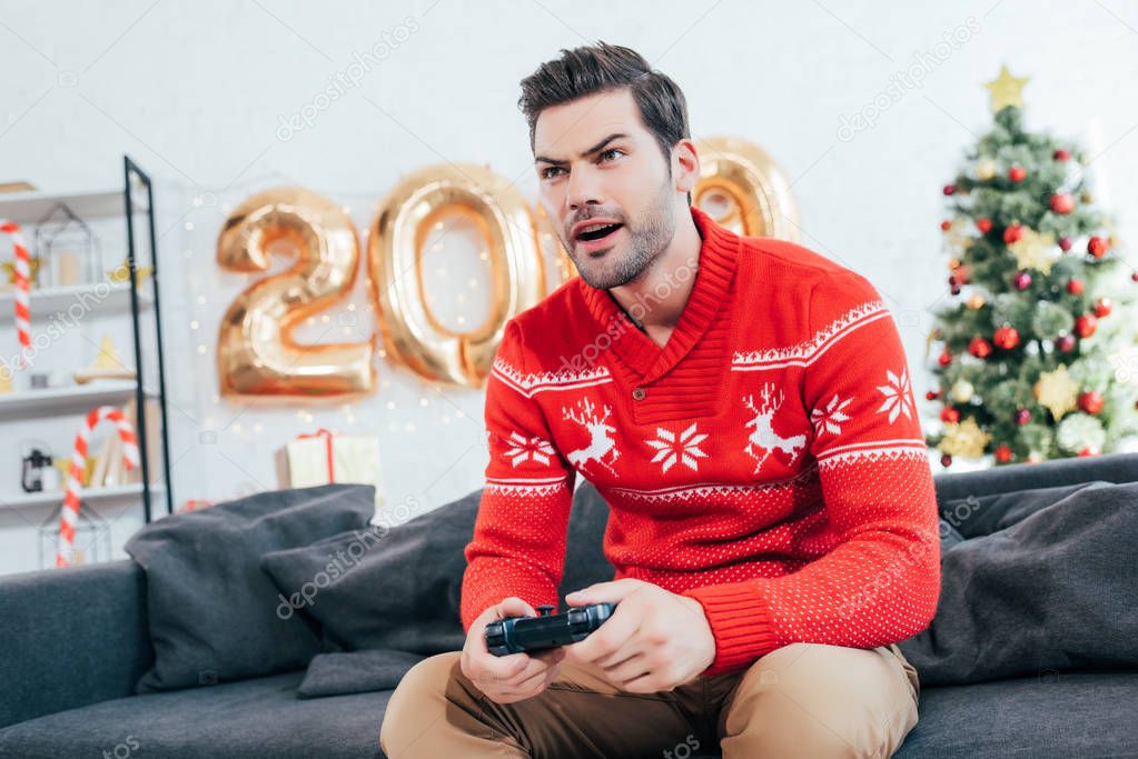 concentrated man playing video game with joystick during new year