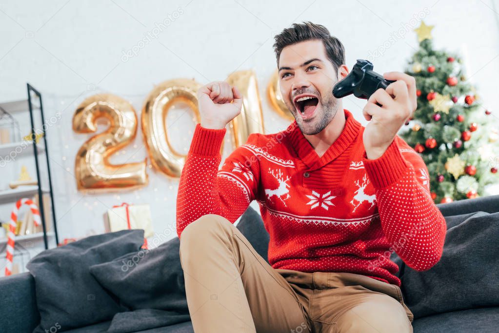 excited man playing video game with joystick during christmas