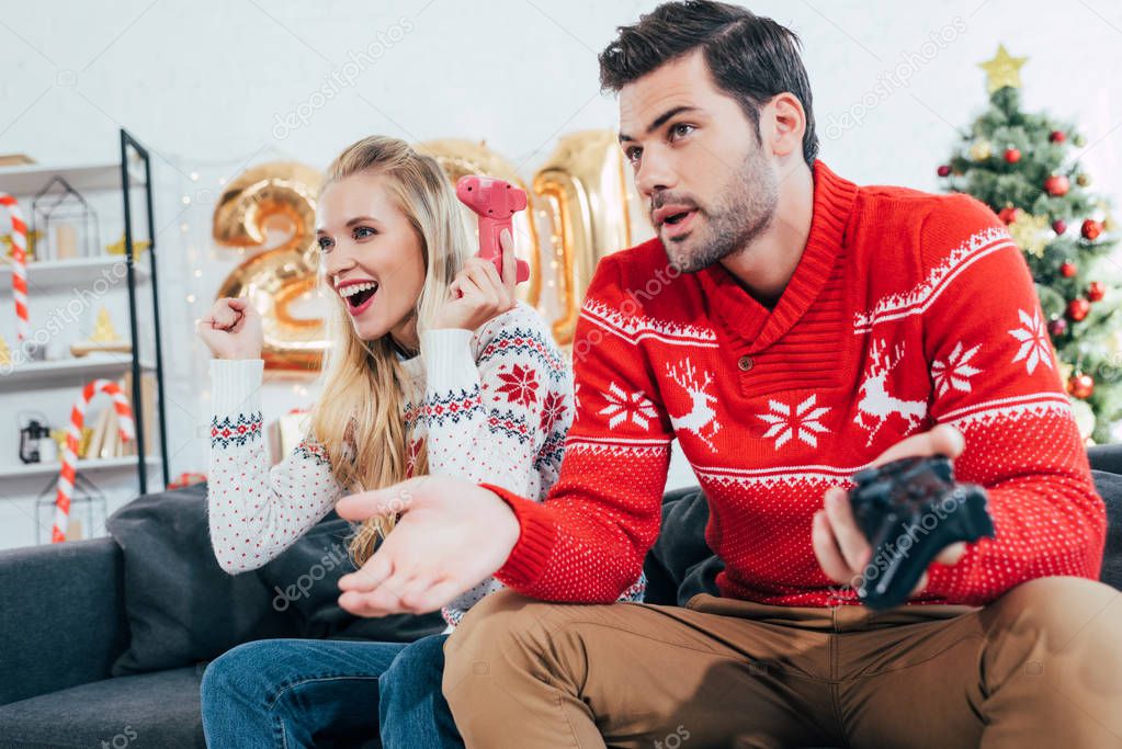 beautiful couple playing video game with joy pads on christmas eve