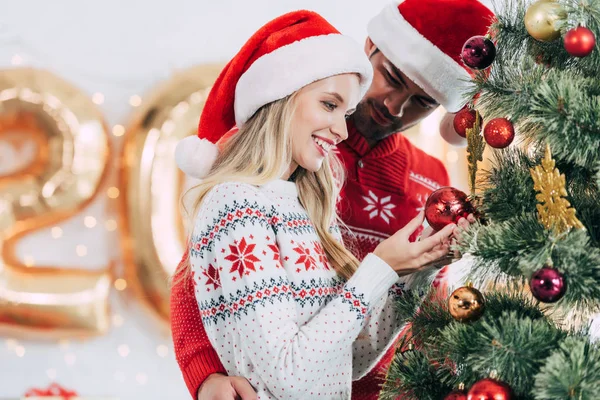 Joven Pareja Santa Sombreros Decorando Árbol Navidad Juntos —  Fotos de Stock