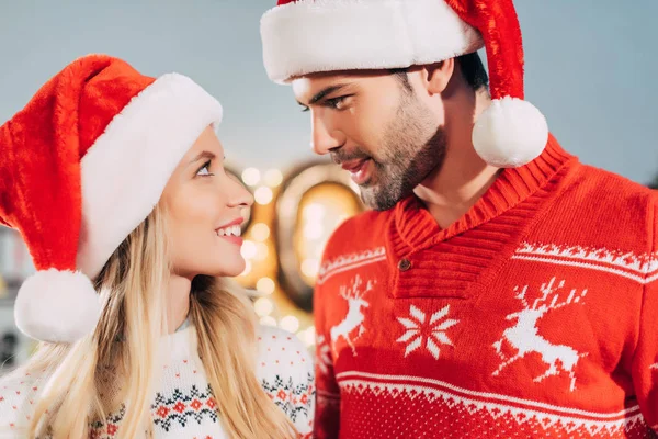 Feliz Pareja Sombreros Santa Mirándose Uno Otro Víspera Navidad — Foto de Stock