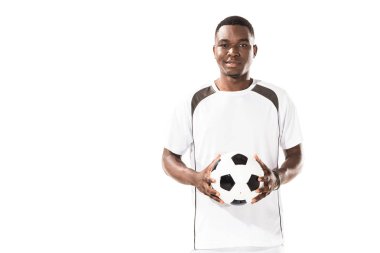 futbol topu tutarak ve üzerinde beyaz izole kamera gülümseyen mutlu genç Afro-Amerikan sporcu