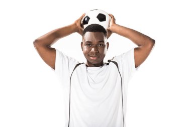 young african american soccer player holding ball above head and smiling at camera isolated on white  clipart