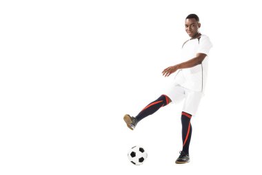 young african american soccer player kicking ball and smiling at camera isolated on white clipart