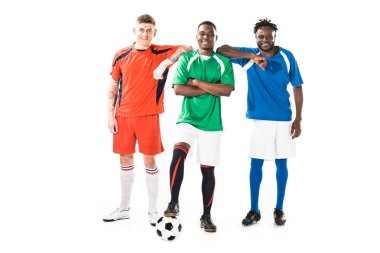birlikte duran ve üzerinde beyaz izole kamera gülümseyen mutlu genç çok ırklı futbol oyuncuları  