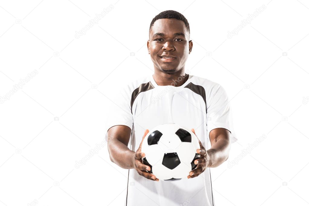 handsome happy young african american sportsman holding soccer ball and smiling at camera isolated on white