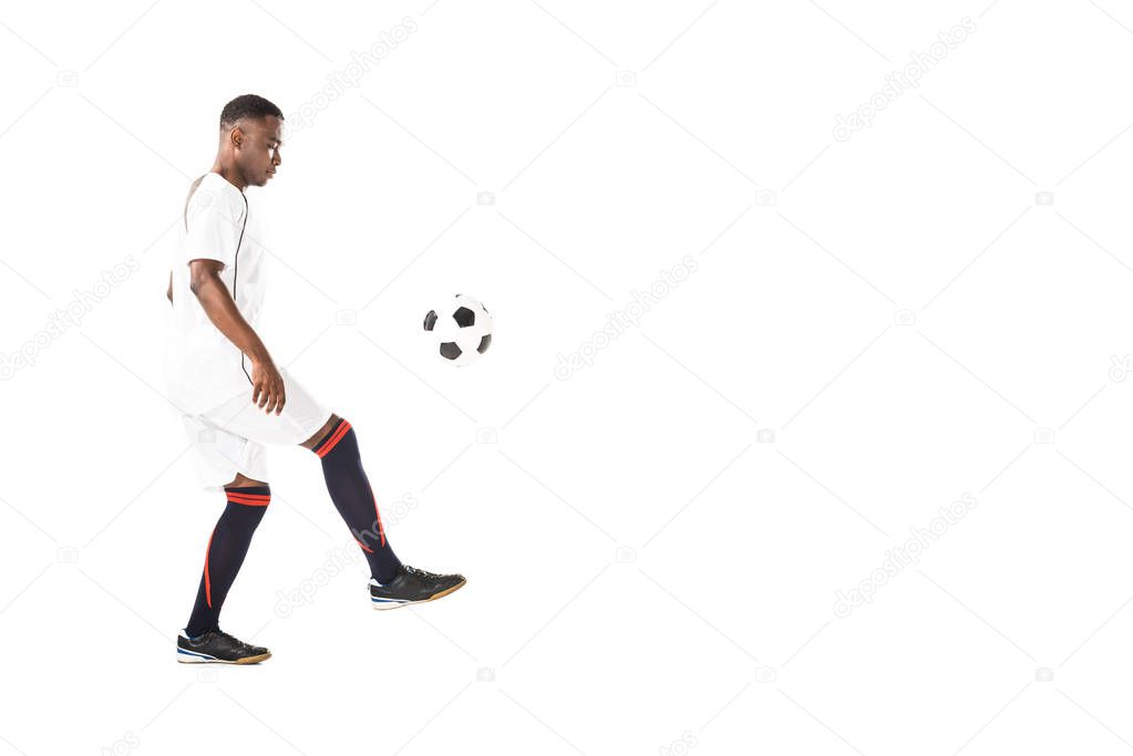 side view of handsome young african american sportsman playing with soccer ball isolated on white