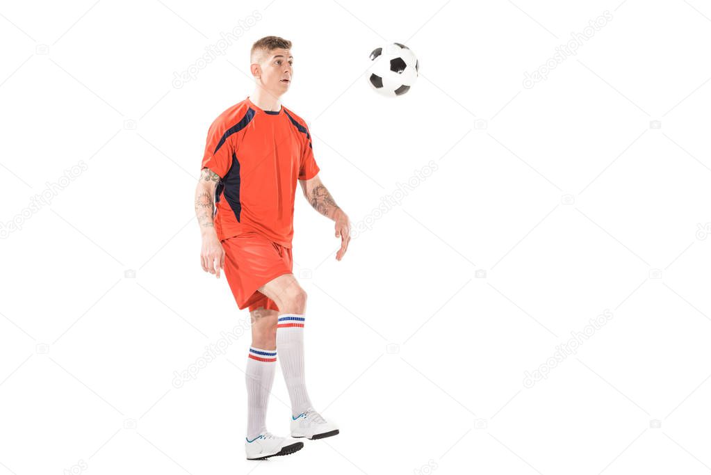 full length view of athletic young soccer player kicking ball isolated on white  