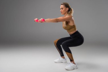 Grey dumbbells ile ağız kavgası yapıyor atletik genç kadın