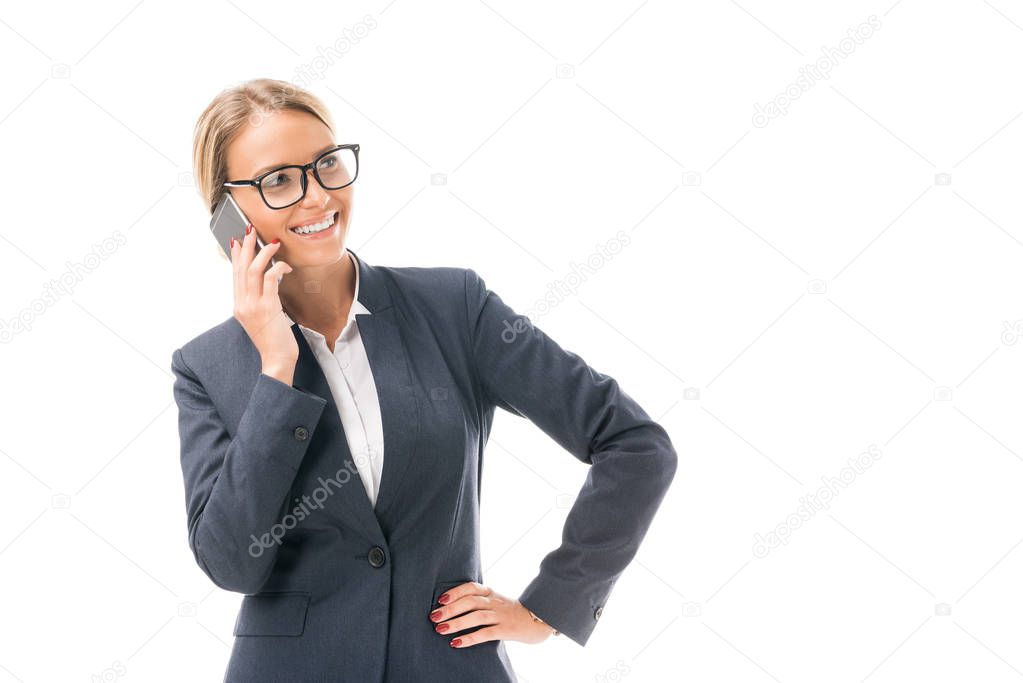 smiling young businesswoman talking by phone and looking away isolated on white