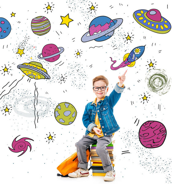 smiling schoolboy pointing up while sitting on pile of books with backpack, isolated on white with fantasy universe, planets and spaceships